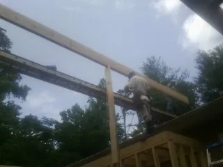 Carpenter setting a ridge beam over a new addition frame — Ice Dam Removal by Roofing Brothers in Hay Springs