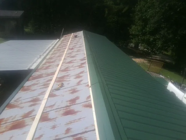 Old rusted panels beside newly installed green metal roofing — Wind Damage Roof Repair by Roofing Brothers in Hay Springs