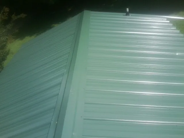 New green metal panels meeting at the ridge of a roof — Flat Roof Repair work by our crew in Hay Springs