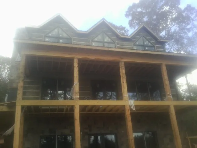 Dormers and porch framing on a large log home under construction — Roof Coating work by our crew in Hay Springs