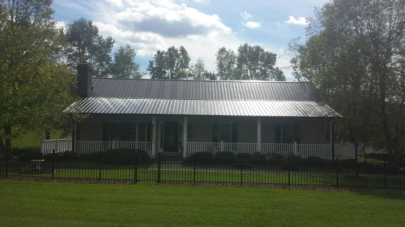 Gray metal roof on a brick ranch with a full width front porch — Gutter Guard Installation work by our crew in Hay Springs