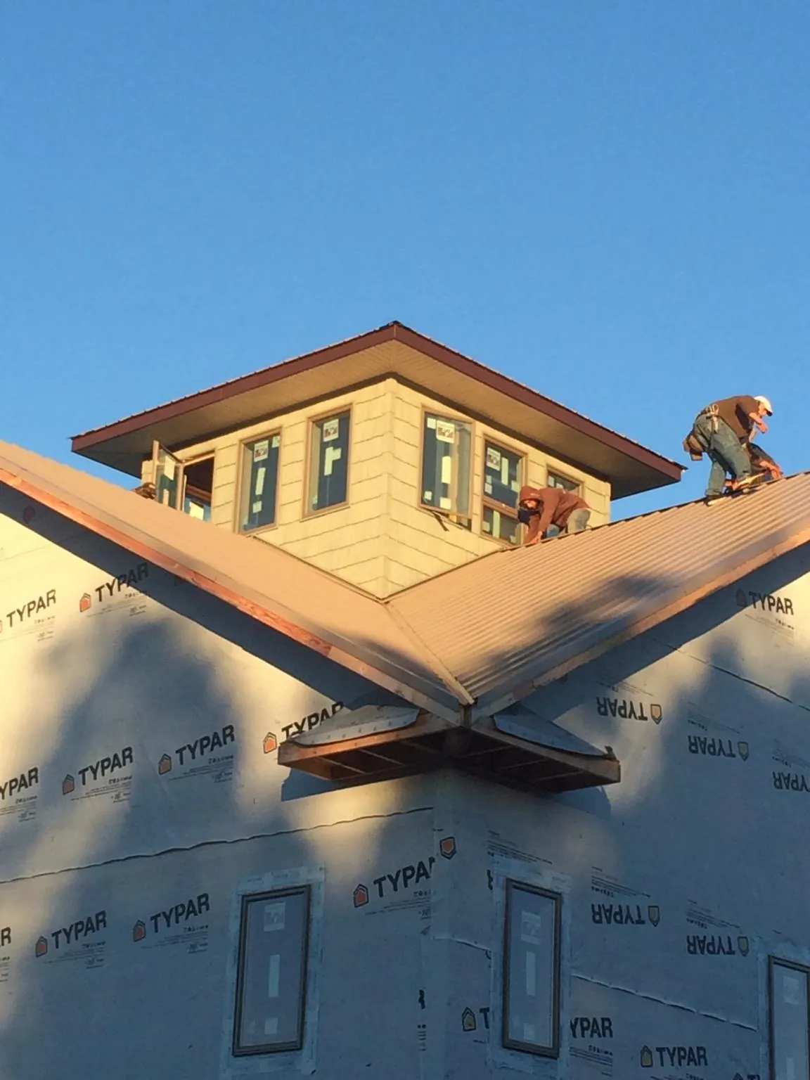 Roofers working around a rooftop cupola on a new metal roof at sunset — Roof Waterproofing in Hay Springs by Roofing Brothers